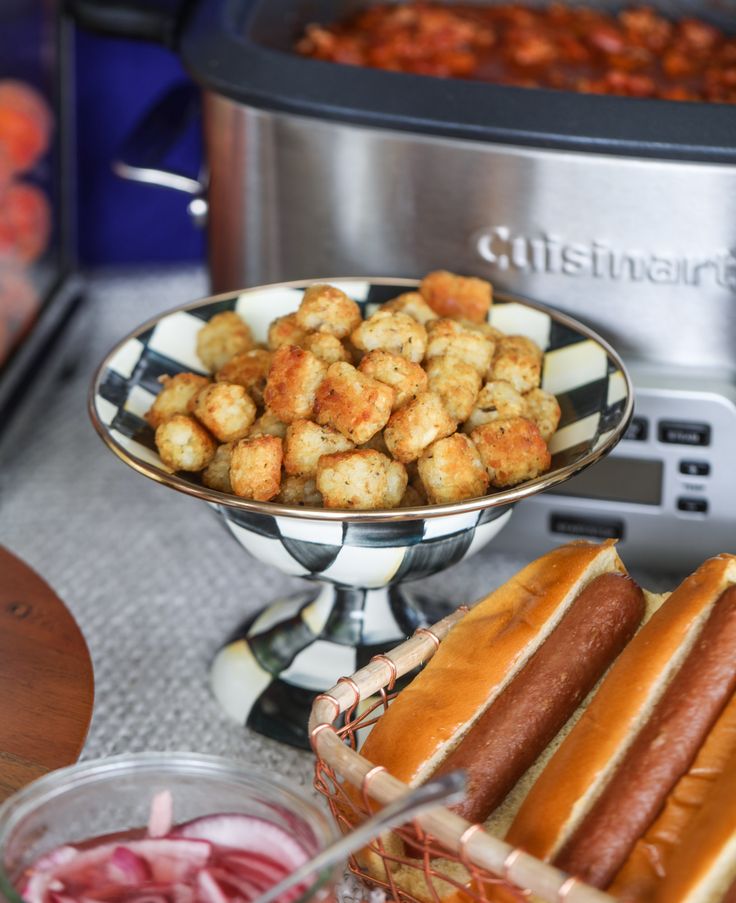 hotdogs, tater tots and other foods are on a table next to an air fryer