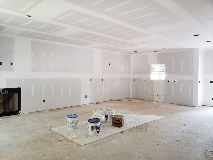 an empty room with white paint on the walls and two buckets next to it