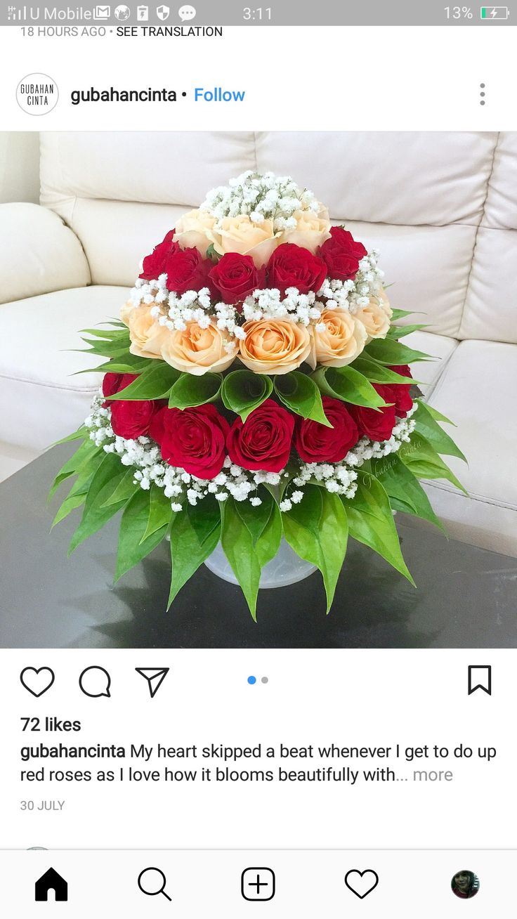 a vase filled with roses on top of a table next to a white couch in a room