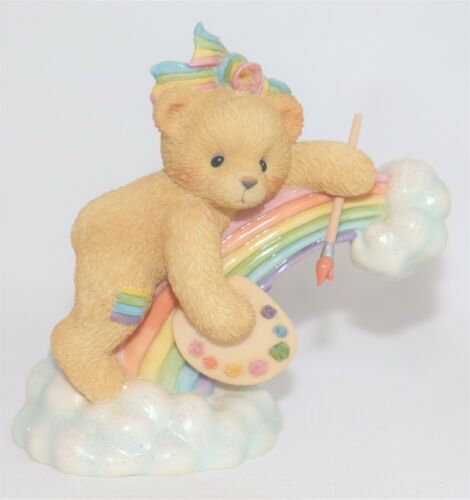 a teddy bear riding on top of a rainbow shaped toy