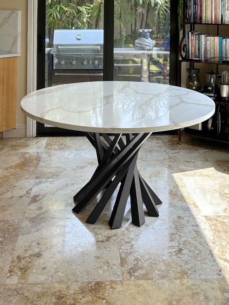 a white table sitting in the middle of a living room next to a book shelf