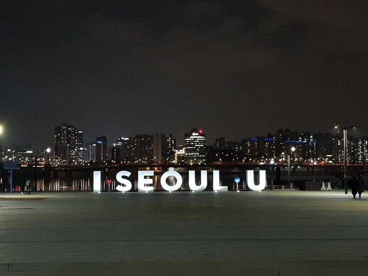 people are standing in front of the illuminated sign that reads i seouul u