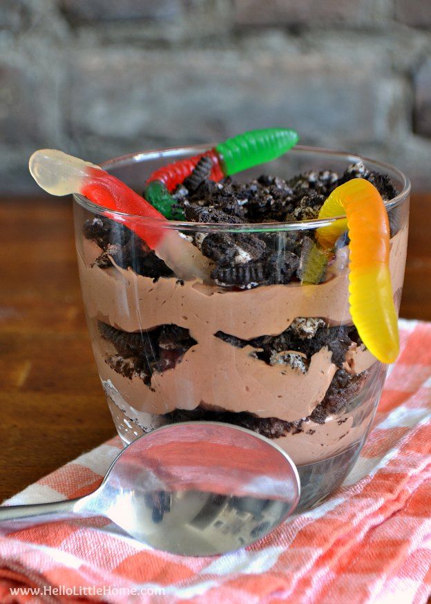 a dessert in a glass on top of a table with spoons next to it