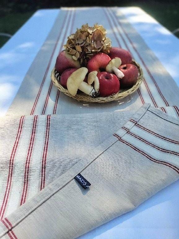 a bowl of apples sitting on top of a table next to a white and red striped napkin