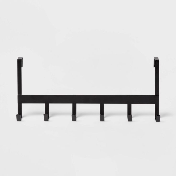 a black metal shelf with four hooks on it