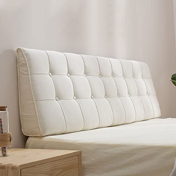 a white bed sitting next to a wooden table with a potted plant on top of it