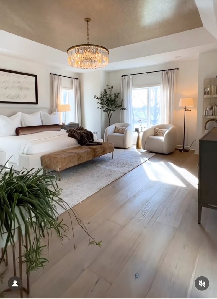 a bedroom with white walls and wood flooring has a chandelier hanging from the ceiling