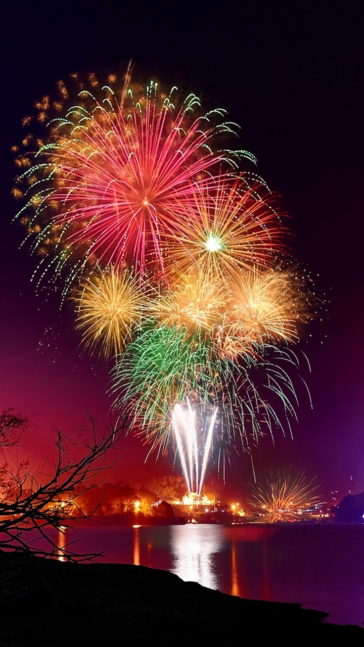 fireworks are lit up in the night sky over water