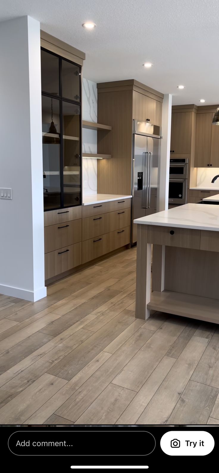 an empty kitchen with wooden floors and stainless steel appliances