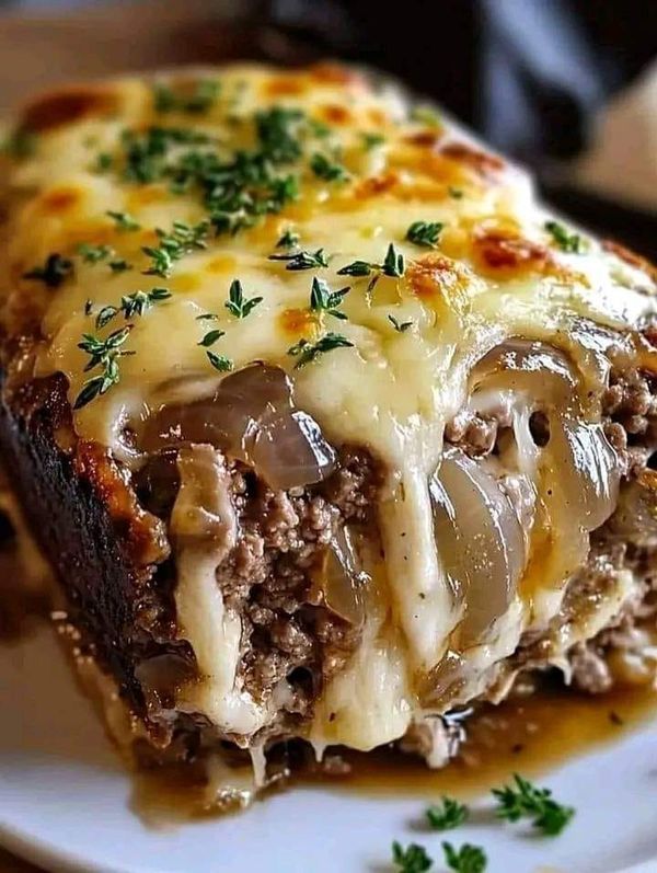 a piece of meatloaf with cheese and onions on a white plate, garnished with parsley