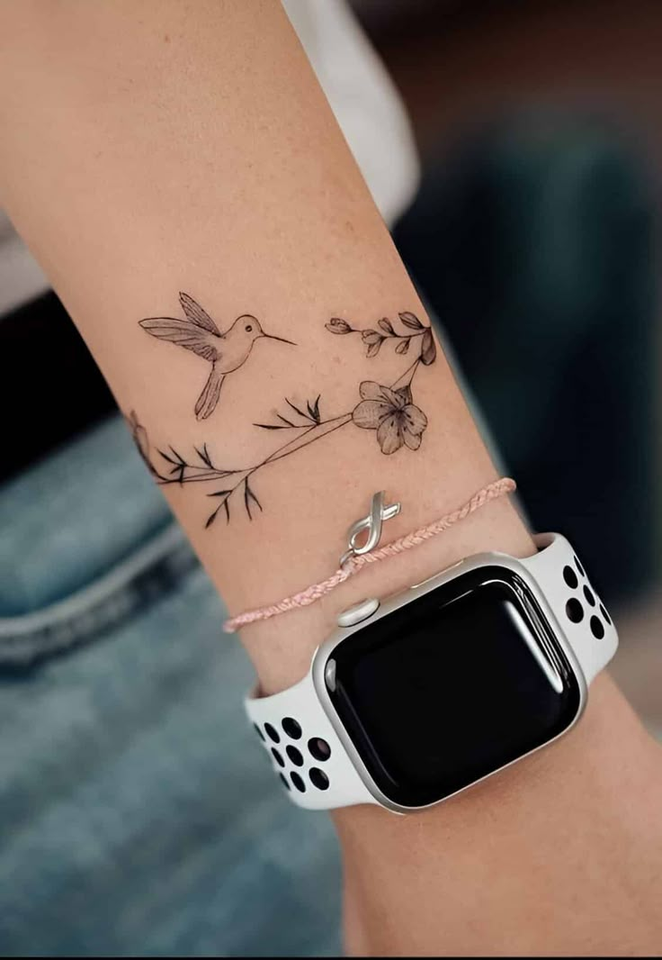 a woman's arm with a bird and flower tattoo on it, she is wearing a white apple watch band