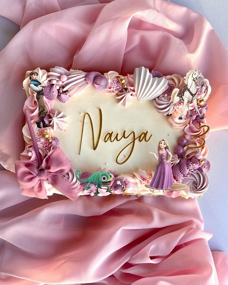 there is a cake with the name avaga on it, surrounded by pink fabric