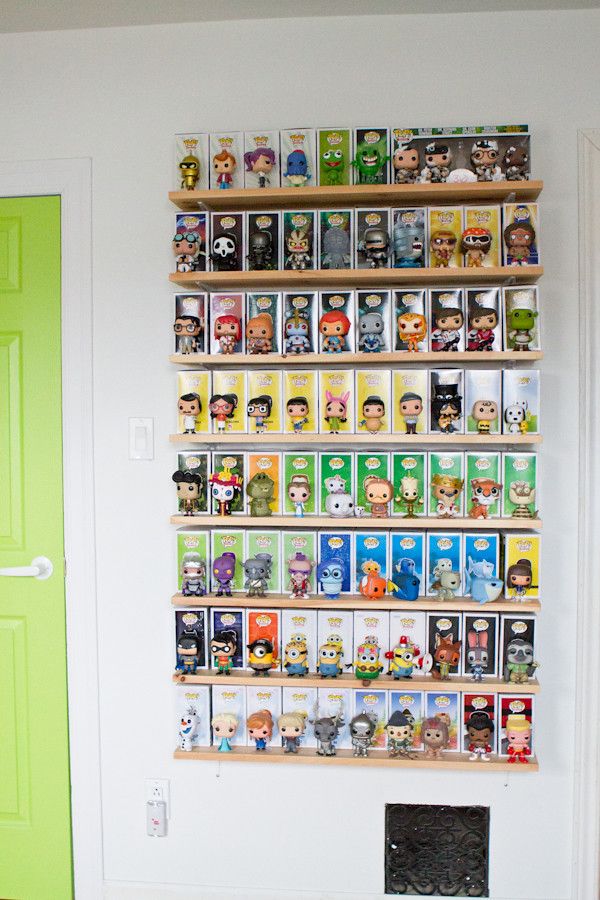 a green door is in front of a white wall with shelves filled with movies and vinyl toys