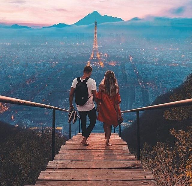 two people walking down a wooden walkway with the eiffel tower in the background