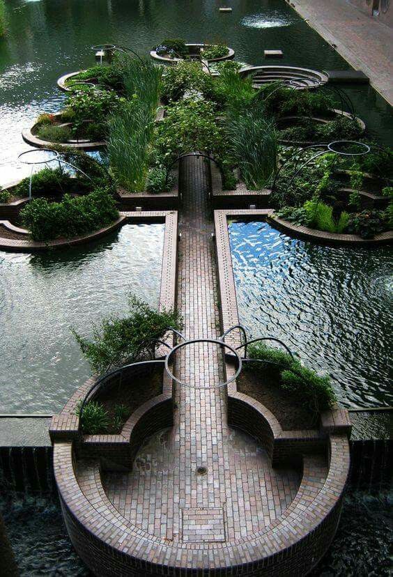 an outdoor garden is shown in the middle of a pond and surrounded by greenery