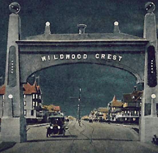 the entrance to wildwood crest is shown in this old time photo with an antique car driving under it