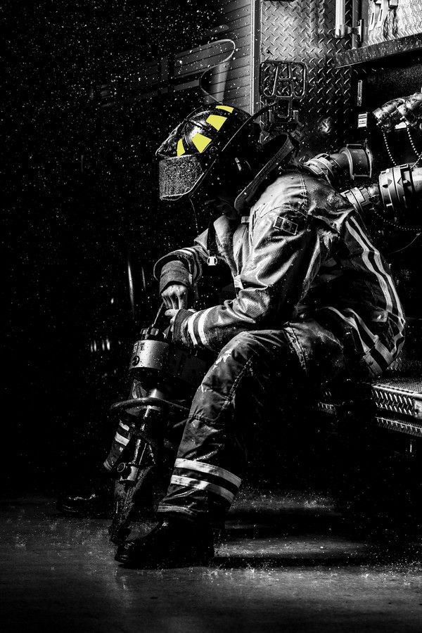 a man sitting on top of a bench wearing a fireman's uniform and helmet