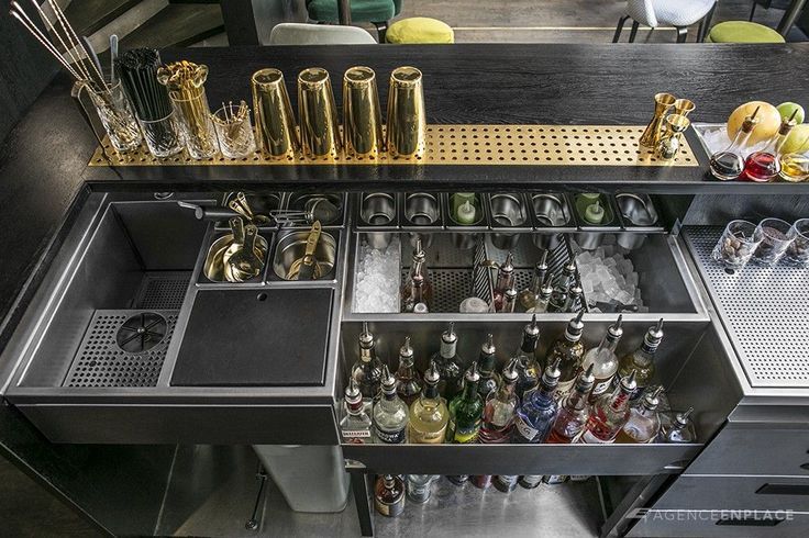 an open drawer in a kitchen filled with lots of bottles and glasses on top of it