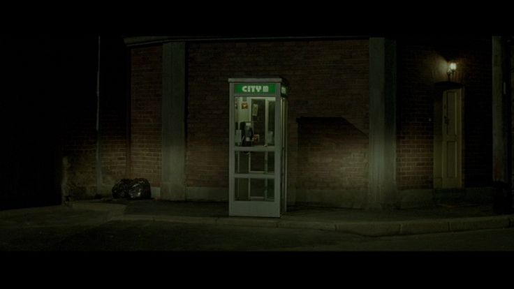 a phone booth sitting on the side of a building at night time with its door open