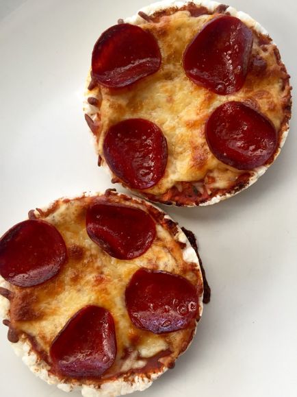 two mini pizzas with cheese and pepperoni on them sitting on a white plate