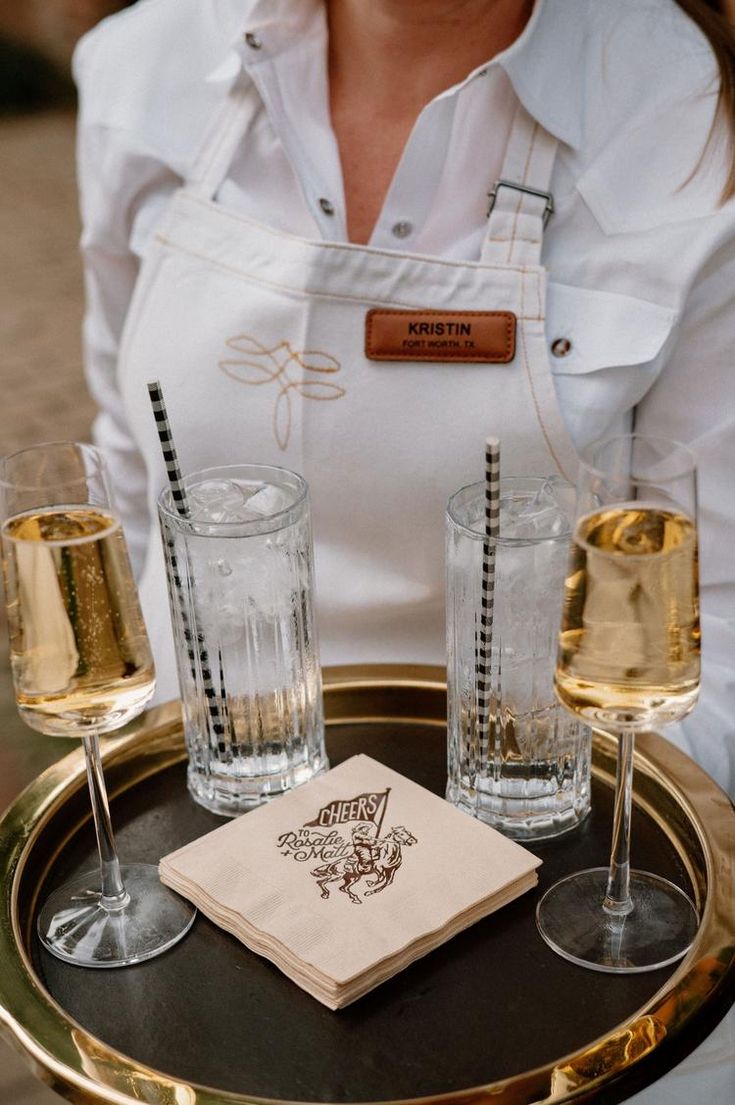 a woman holding a tray with three glasses on it and a napkin in front of her