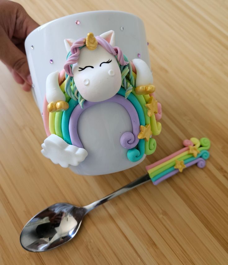 a cup with a unicorn on it next to a spoon