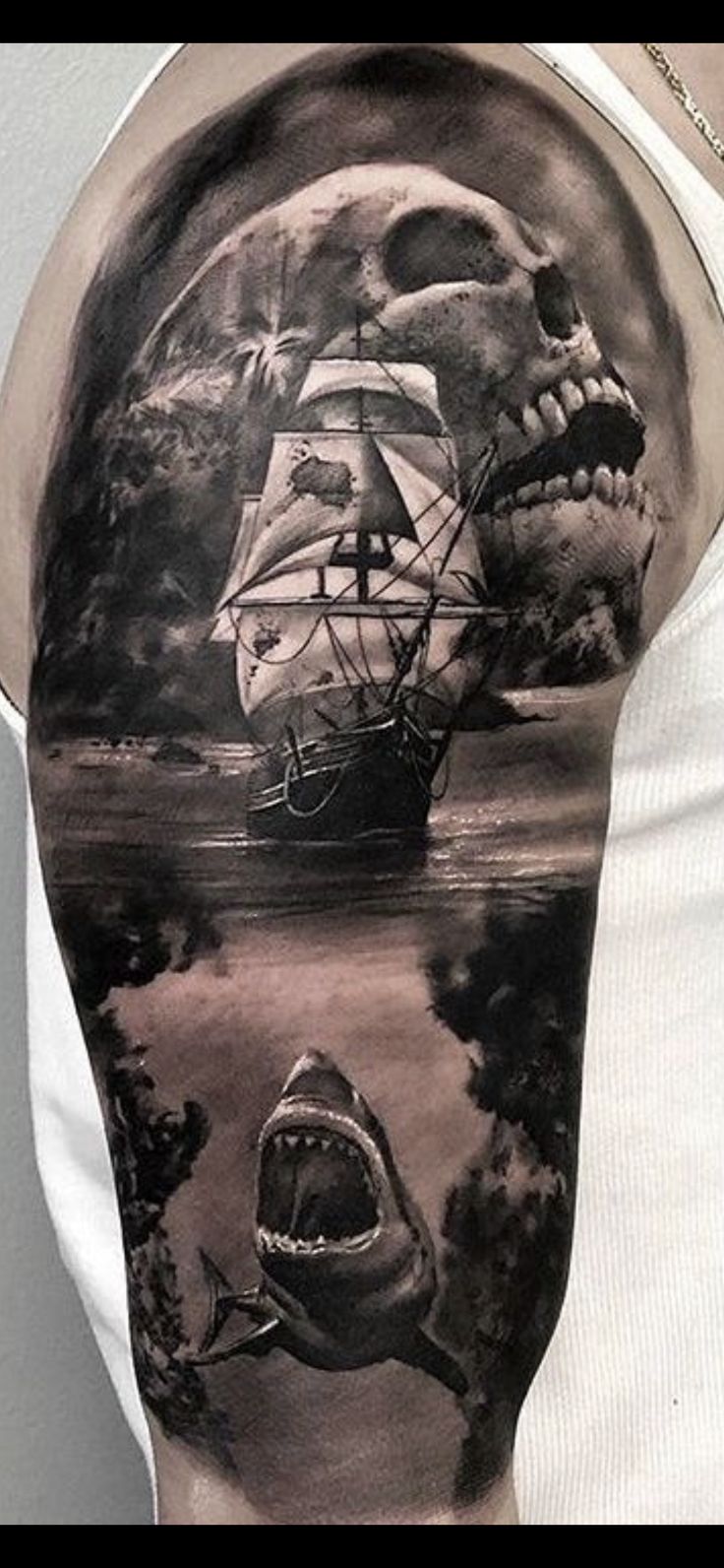 a man's arm with a ship and shark in the water, on which he is