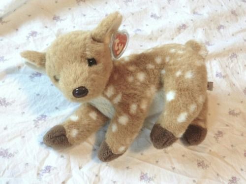 a small stuffed deer laying on top of a bed