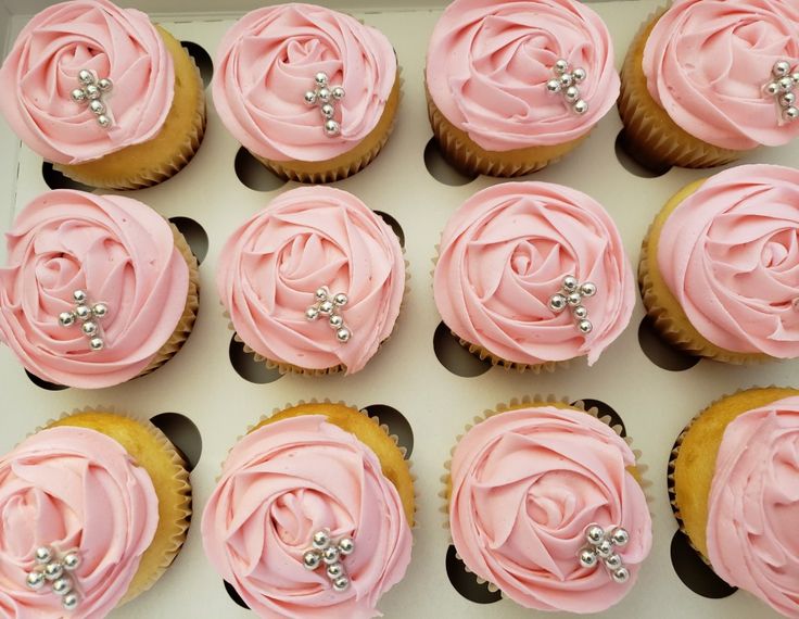 twelve cupcakes with pink frosting and pearls on the top are arranged in a box