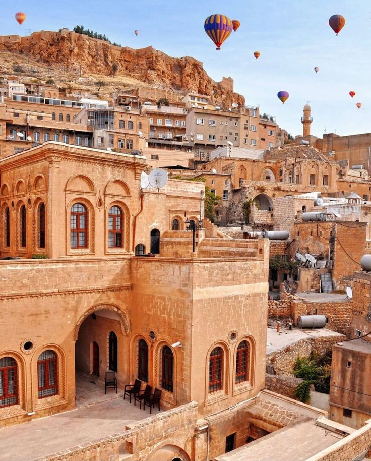 an old city with hot air balloons in the sky