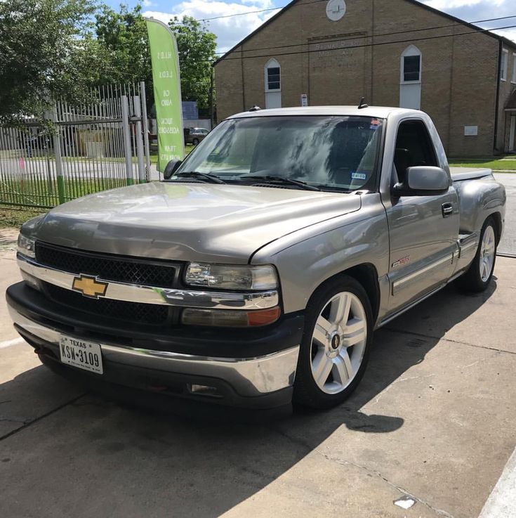 a silver truck is parked on the side of the road in front of a building