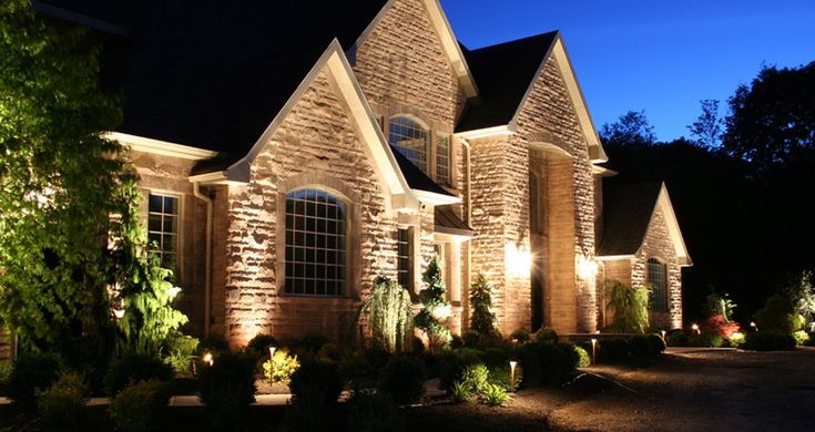 a house that is lit up at night with lights on the front and side of it