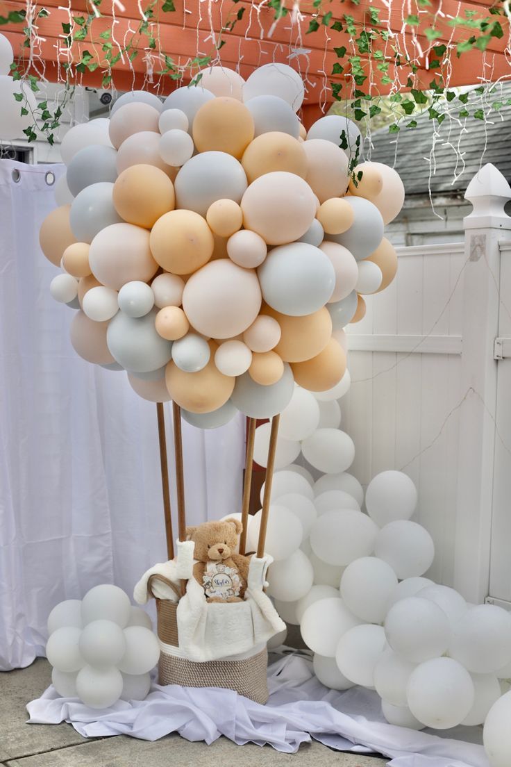 a teddy bear is sitting in a basket with balloons attached to the back of it