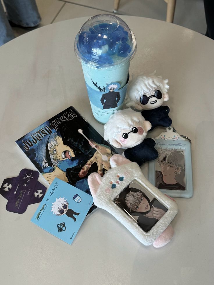 stuffed animals and books on a table next to a cup of coffee with blue liquid