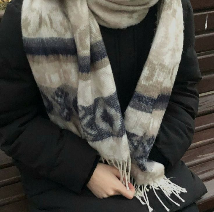 a woman sitting on a bench wearing a scarf