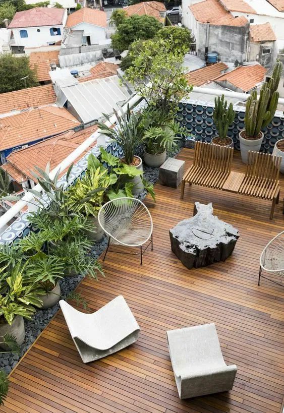 an elevated deck with chairs and plants on it, overlooking the city below in this aerial view