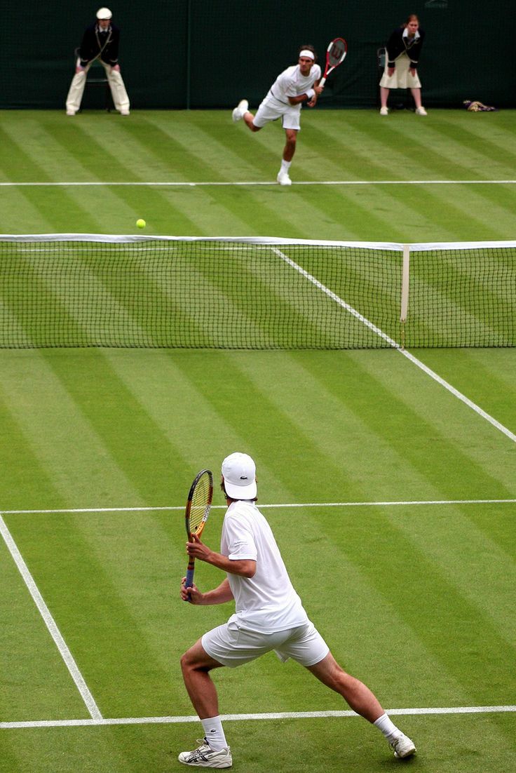 two men playing tennis on a grass court