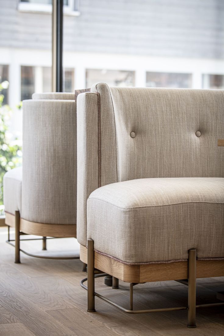 two beige chairs sitting next to each other on top of a hard wood floor in front of a window