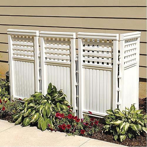 a white garden divider sitting next to flowers and plants on the side of a building