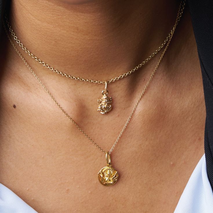 a close up of a woman wearing a necklace with two pendants on her neck