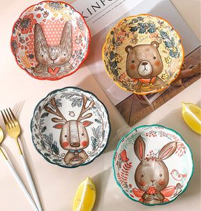 three plates with animals painted on them next to forks and spoons near a book