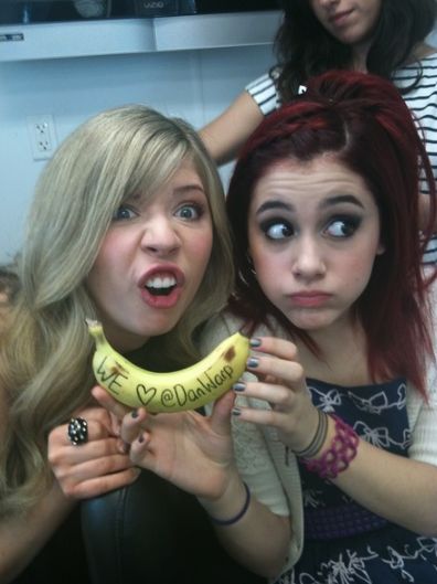 two young women holding up a banana with the words i love you written on it