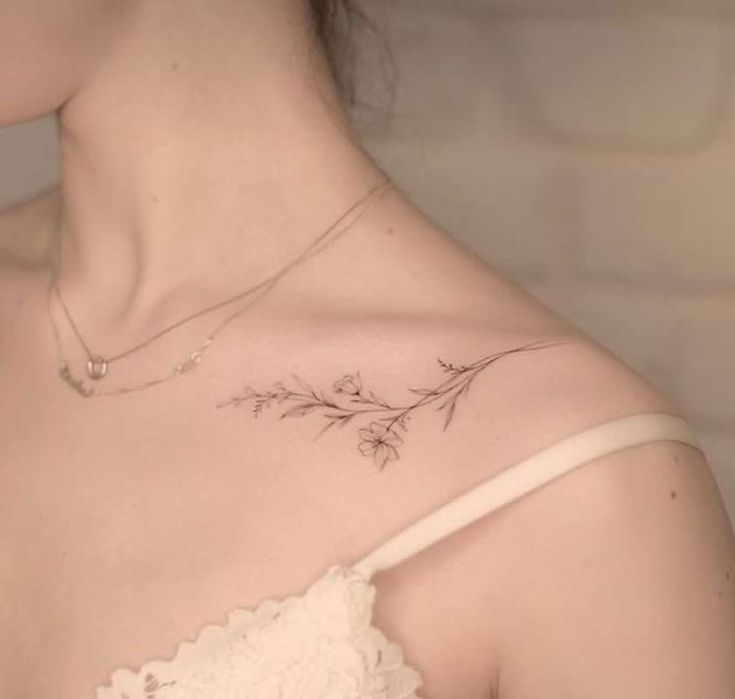 a woman's shoulder with a flower tattoo on the left side of her neck