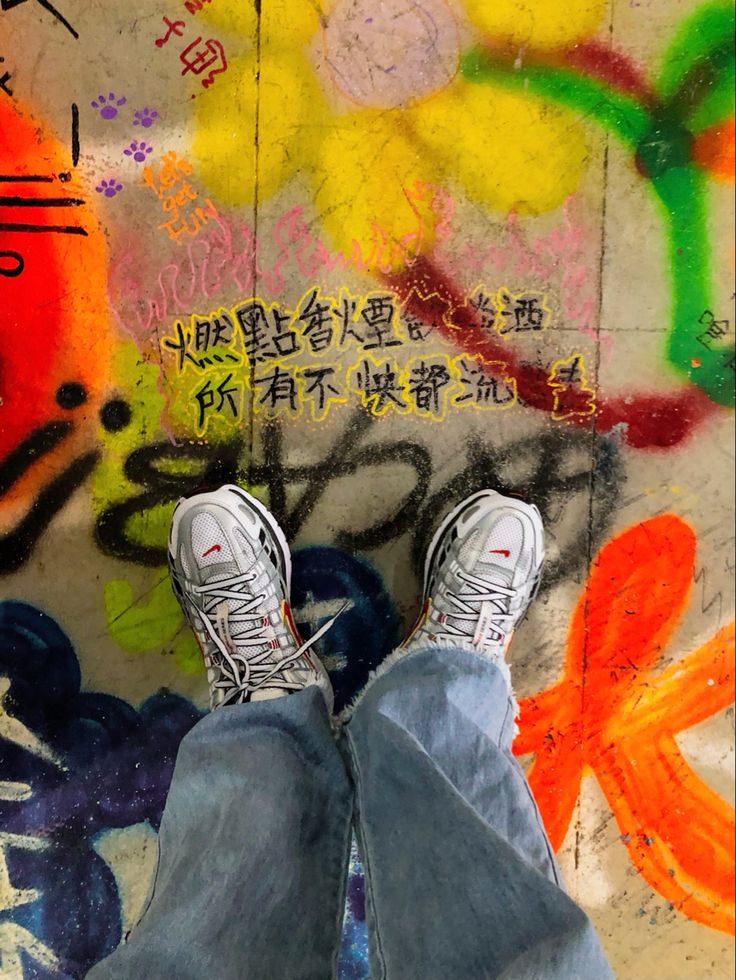 a person with their feet up on a skateboard in front of graffiti covered walls