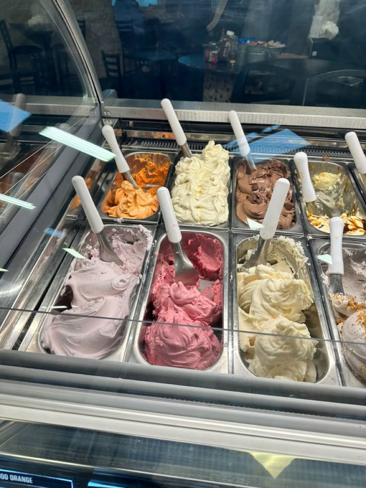 an assortment of ice creams in trays on display at a deli or restaurant