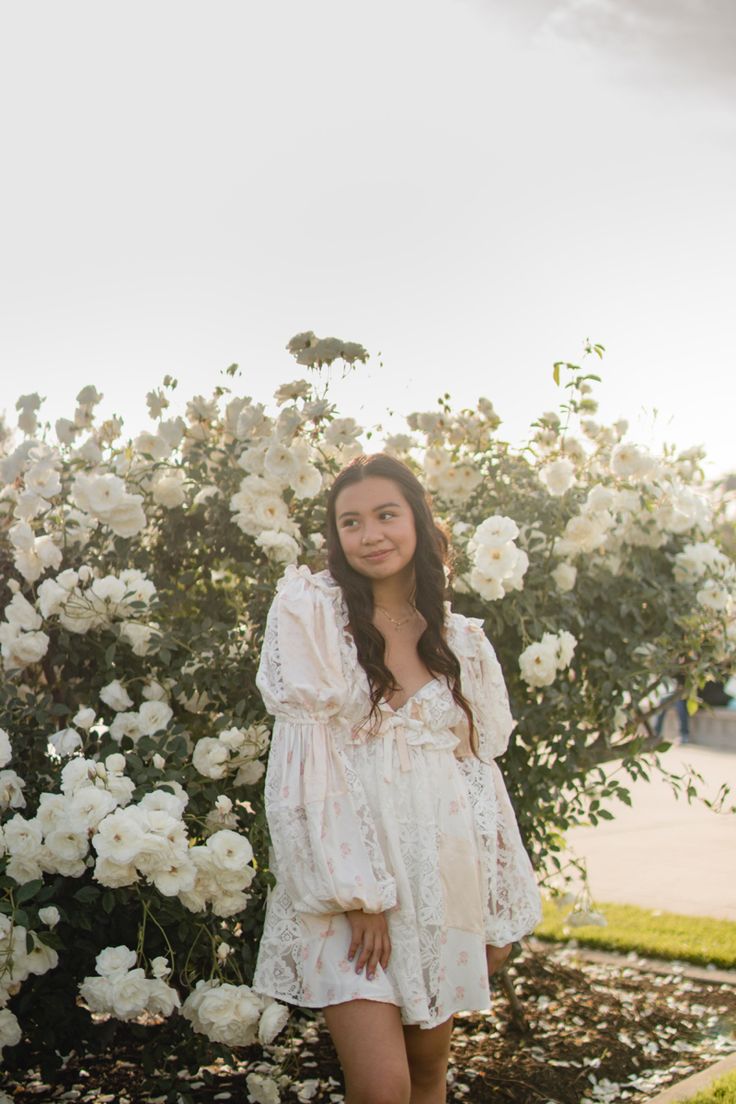 a woman standing in front of white flowers