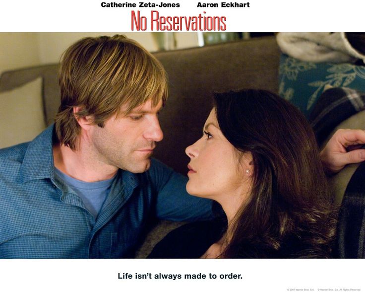 a man and woman sitting next to each other in front of a poster for the movie no reservations