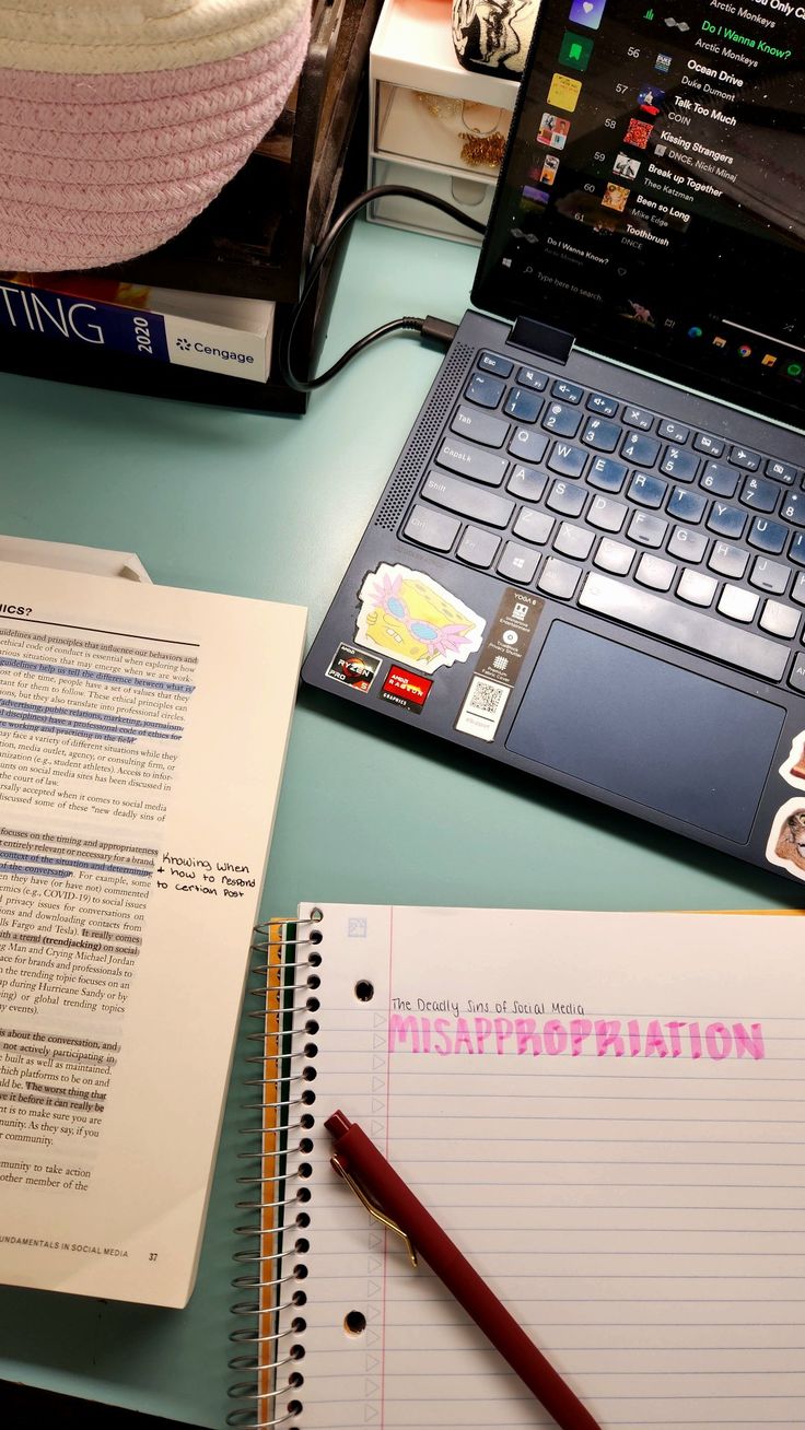 an open laptop computer sitting on top of a desk next to a notebook and pen