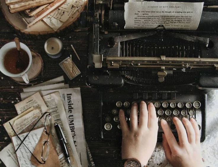 a person typing on an old typewriter surrounded by papers and other things that are scattered around