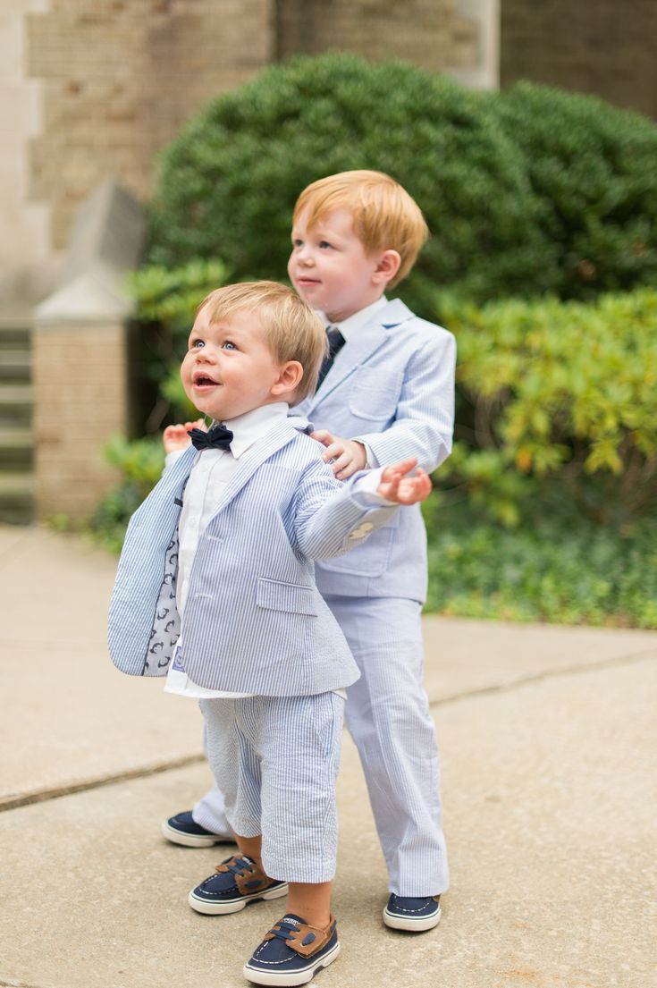 two young boys dressed in suits and ties, one holding the other's hand